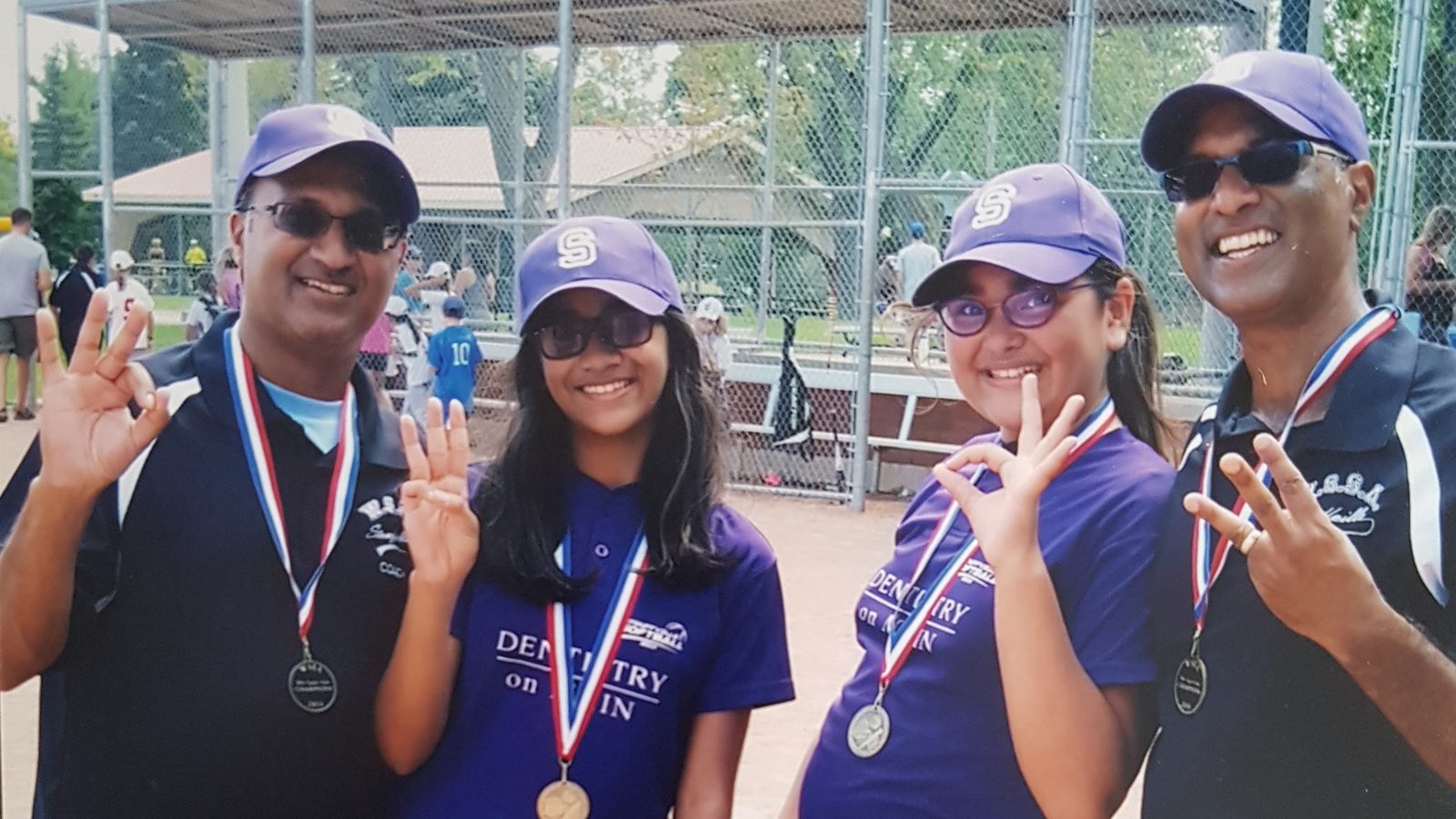 David Parmer, right, with a fellow coach and two players from a Stouffville girls' softball team, all wearing tournament medals